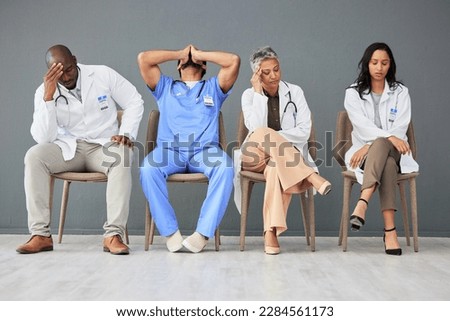 Exhausted, tired and doctors waiting in the hospital with frustration, sad and burnout. Upset, professional and team of healthcare workers sitting in a line in a hallway for meeting in medical clinic Royalty-Free Stock Photo #2284561173