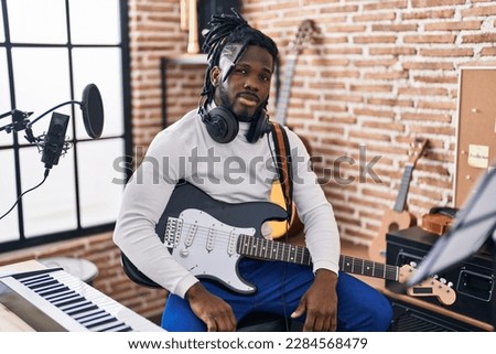 African american woman artist playing electrical guitar at music studio