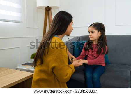 Concerned loving mother talking to her young daughter about divorce and child custody while sitting on the sofa