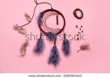 Dream catcher with materials on pink background