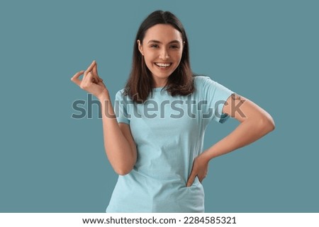 Young woman snapping fingers on blue background Royalty-Free Stock Photo #2284585321