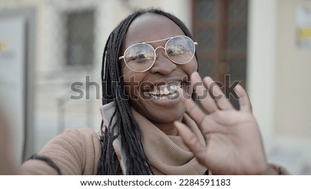 African woman taking selfie waving to the camera at street
