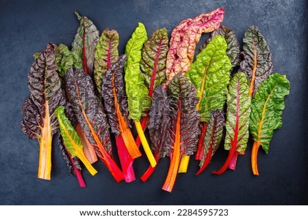 Raw colourful chard offered as a close-up on a rustic black board  Royalty-Free Stock Photo #2284595723