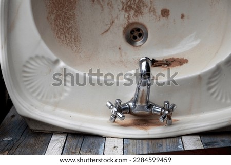 Image of a sink in a state of disrepair, an obsolete and unused object on a background of old wood. Housing renovation concept. Royalty-Free Stock Photo #2284599459