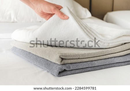woman puts fresh clean towels on the bed in a hotel guest room, close-up. Woman's hand touches soft terry towels after cleaning the room Royalty-Free Stock Photo #2284599781