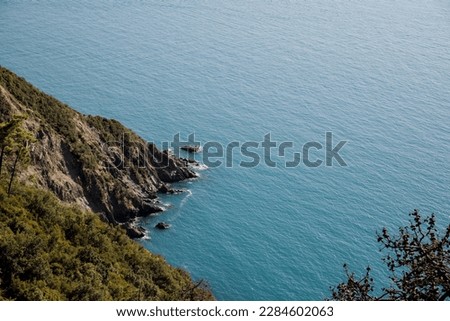 Capture the beauty and power of nature with this stunning photo of a rugged cliff merging into the sea in 5 Terre. The rocky terrain and turbulent waves create a dynamic contrast