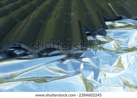 Aluminum foil insulation sheet installed under the corrugated concrete roof tiles during construction for reflection heat radiation and protect heat in to house.  Attic insulation.