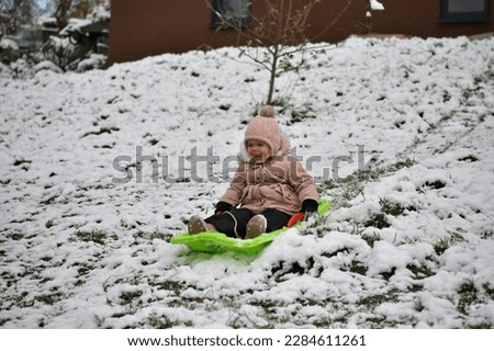The smile on the little girl's face while sledding on snow in winter