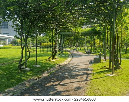 Archway, trees grow in the park, in the middle of the city, there are lawns and gardens, with a tall building in the background. Royalty-Free Stock Photo #2284616803