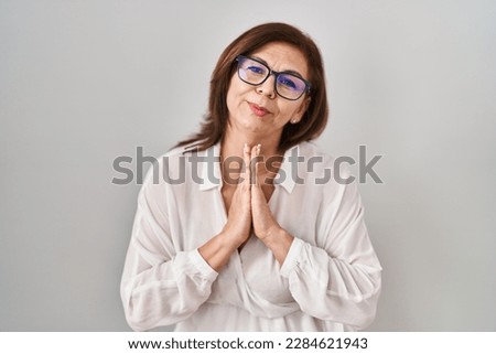 Middle age hispanic woman standing over isolated background begging and praying with hands together with hope expression on face very emotional and worried. begging.  Royalty-Free Stock Photo #2284621943