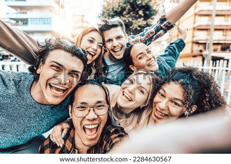 Multicultural best friends having fun taking group selfie portrait outside - Young students laughing celebrating outside the campus on city street - Portrait of teens guys and girls enjoying vacation Royalty-Free Stock Photo #2284630567