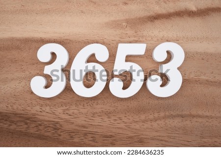 White number 3653 on a brown and light brown wooden background.