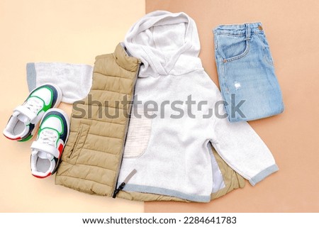 Vest,jumper,hooded sweatshirt,knitted,jeans pants with sneakers.Set of baby children's clothes,clothing,accessories for spring,autumn,winter on brown background.Fashion kids outfit.top view.