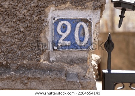 Vintage grunge square metal rusty plate of number of street address with number 20 closeup