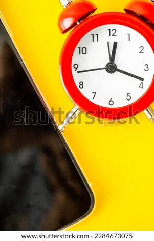 Red clock on a yellow background and cell phone beside it. Mention the schedule for personal care, physical exercise and time for medical support remedies for rheumatism, arthrosis and labyrinthitis.