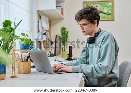 Young male college student sitting at desk at home using laptop Royalty-Free Stock Photo #2284690089