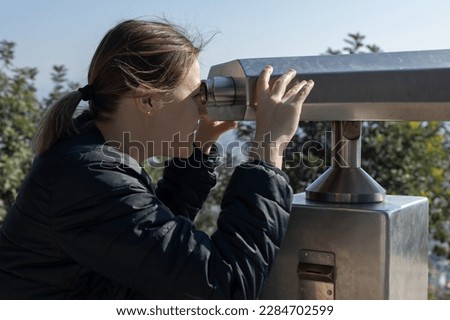 Girl tourist uses panoramic sightseeing binoculars to survey the area. High quality photo