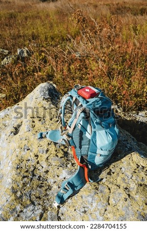First aid kit is in a backpack, camping equipment, a backpack stands on a stone in the mountains, a red first-aid kit, backpack straps, tourist equipment. High quality photo