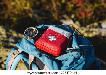 Compass first aid kit are in a backpack, a navigator in the taiga, a first aid kit in emergency situations, a white cross, medicines in a red bag. High quality photo Royalty-Free Stock Photo #2284704241