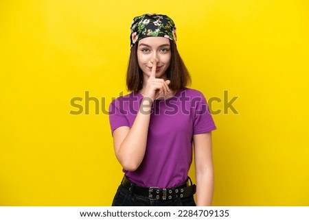 Young Ukrainian woman isolated on yellow background showing a sign of silence gesture putting finger in mouth
