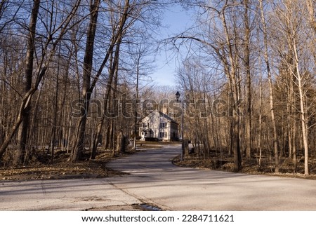Old house with a chimney with shuttered windows in the park in the early spring. Spring season. Sunny day. winding road leading to the house