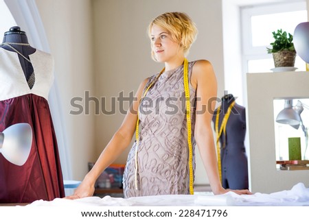 Young attractive needlewoman in studio standing at workplace