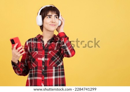 Happy androgynous person listening to music with mobile and headphones