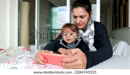 Mother and toddler child looking at cellphone screen