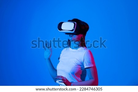 Brunette woman in VR glasses. Confident young woman in virtual reality headset pointing in the air while working in studio.