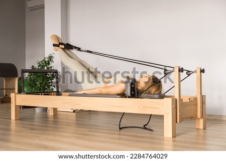 Woman training pilates on the reformer bed. Reformer pilates studio machine for fitness workouts in gym. Fit, healthy and strong authentical body. Fitness concept Royalty-Free Stock Photo #2284764029