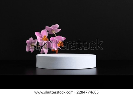 White round podium pedestal cosmetic beauty product goods branding design presentation empty mockup on black background with shadows and beautiful pink orchid flowers  cosmetic mockup Royalty-Free Stock Photo #2284774685