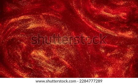 Abstract shimmers and swirls of gold particles in a red liquid. A mysterious glistening background. Particles of gold dust in the red fluid macro photo.