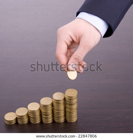 Hand put coin to money staircase on wood desk