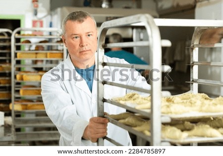 Baker pushing trolley with baked bread. High quality photo