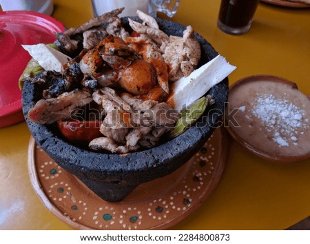 tasty pork and sausages prepared in a molcajete with sauce Royalty-Free Stock Photo #2284800873