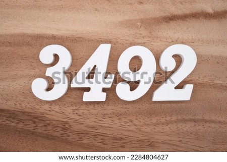 White number 3492 on a brown and light brown wooden background.