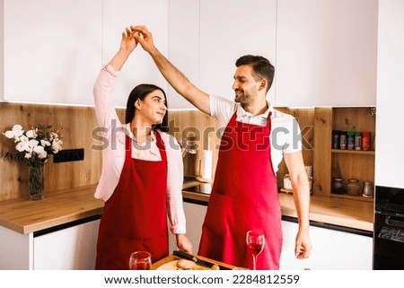 Happy caucasian married couple enjoying dancing together by moving body toward each other on a valentine night date in the kitchen at home