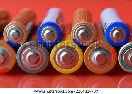 Used AA and AAA alkaline electric bateries lined up in a row on red background Royalty-Free Stock Photo #2284824739
