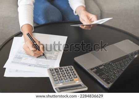 Deduction planning concept. Asian young woman hand using calculator to calculating balance prepare planning filling 1040 tax form business individual income for pay money form personal tax reduction.