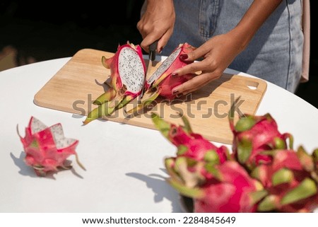 Dragon Fruit. Tropical Fruits, Healthy dragon fruits. Pitaya cut into two halves. Close-up of female hands cutting dragon fruit. dragon fruit cut into two halves.