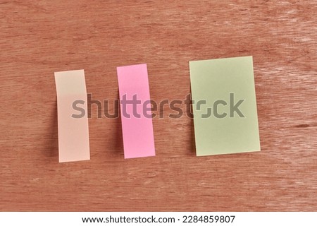 sticky notes, yellow, pink and beige color blank note papers for your message on wooden surface background, mock-up template with copy space