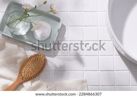 A pastel tray in rectangle shape with a flower vase and a cotton pad placed on, wooden brush with towel and wash basin displayed. Blank space for cosmetic product promotion Royalty-Free Stock Photo #2284866307