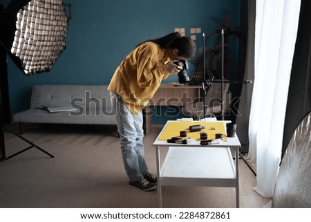 Photographer with SLR camera taking a picture of a product. Shooting beauty products on the table in home studio. Copy space