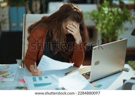 stressed modern middle aged small business owner woman working with documents in the modern green office. Royalty-Free Stock Photo #2284880097