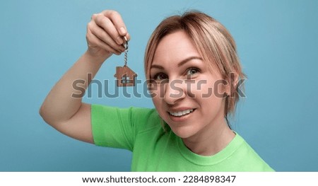 close-up of a happy joyful cute blond girl in a casual look who shows off buying a home on a blue background