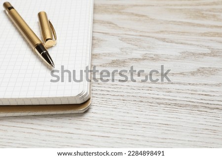 Ballpoint pen and notebook on wooden table, space for text