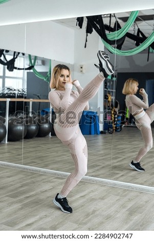 Attractive sporty girl smiling and looking at the camera behind a mirror during body exercises in a fitness class. sport. Healthy Lifestyle Royalty-Free Stock Photo #2284902747