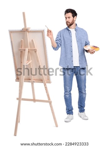 Man painting against white background. Using easel to hold canvas