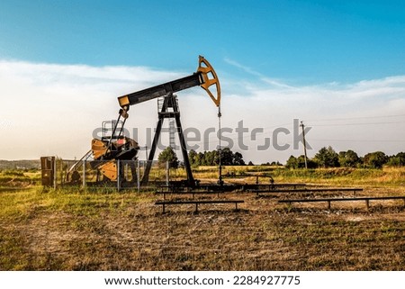 Oil and gas industry. Working oil pump jack on oil field at sunset. Industrial theme