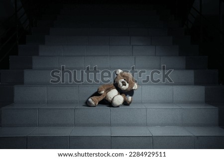 Lonely teddy bear on grey stairs indoors Royalty-Free Stock Photo #2284929511